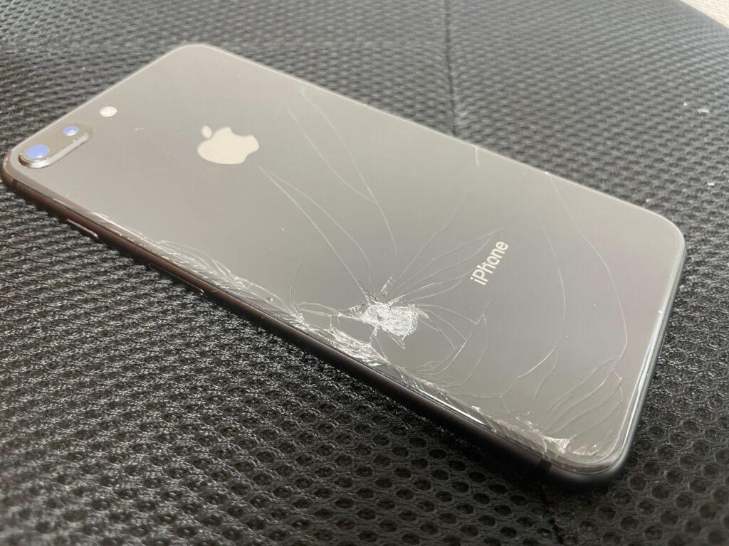 iPhone 8 Plusブラックの背面ガラスが割れている写真です。一か所に打痕があり、そこから割れてしまった事が見て取れます。